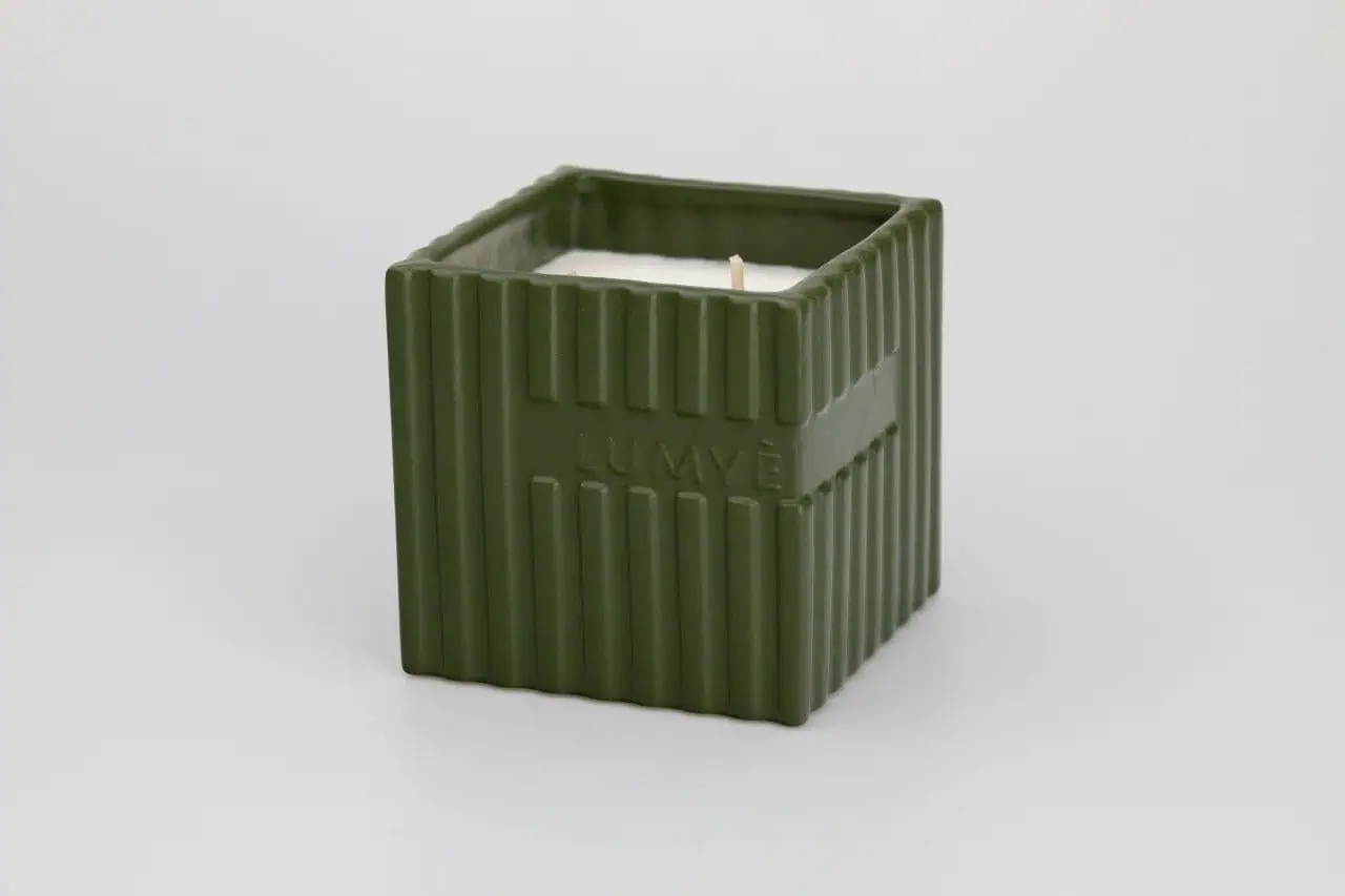 Zielona świeca w kwadratowej ceramicznej podstawce